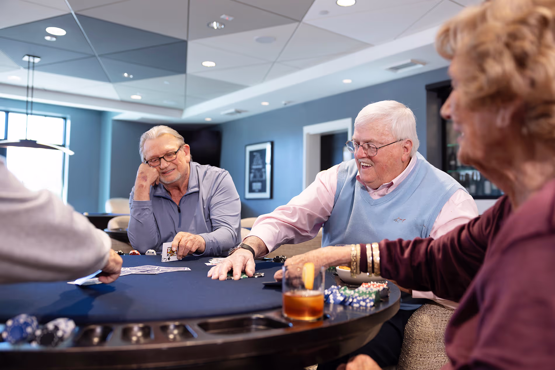 Group of seniors gathered around a table, enjoying a lively game of poker, with smiles and friendly competition in a relaxed setting.