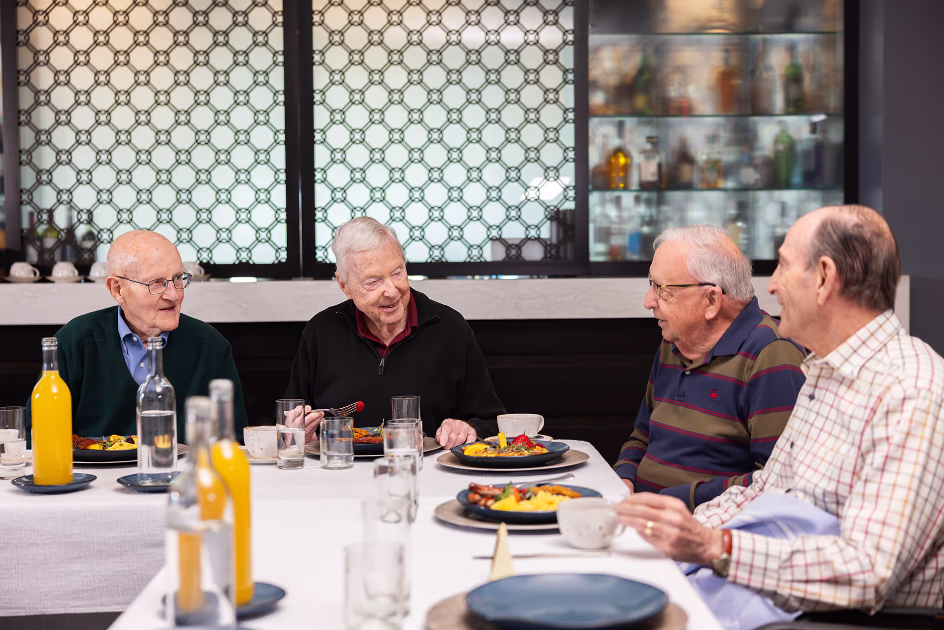 Group of senior men enjoying breakfast together, sharing conversation and laughter in a casual and friendly atmosphere.