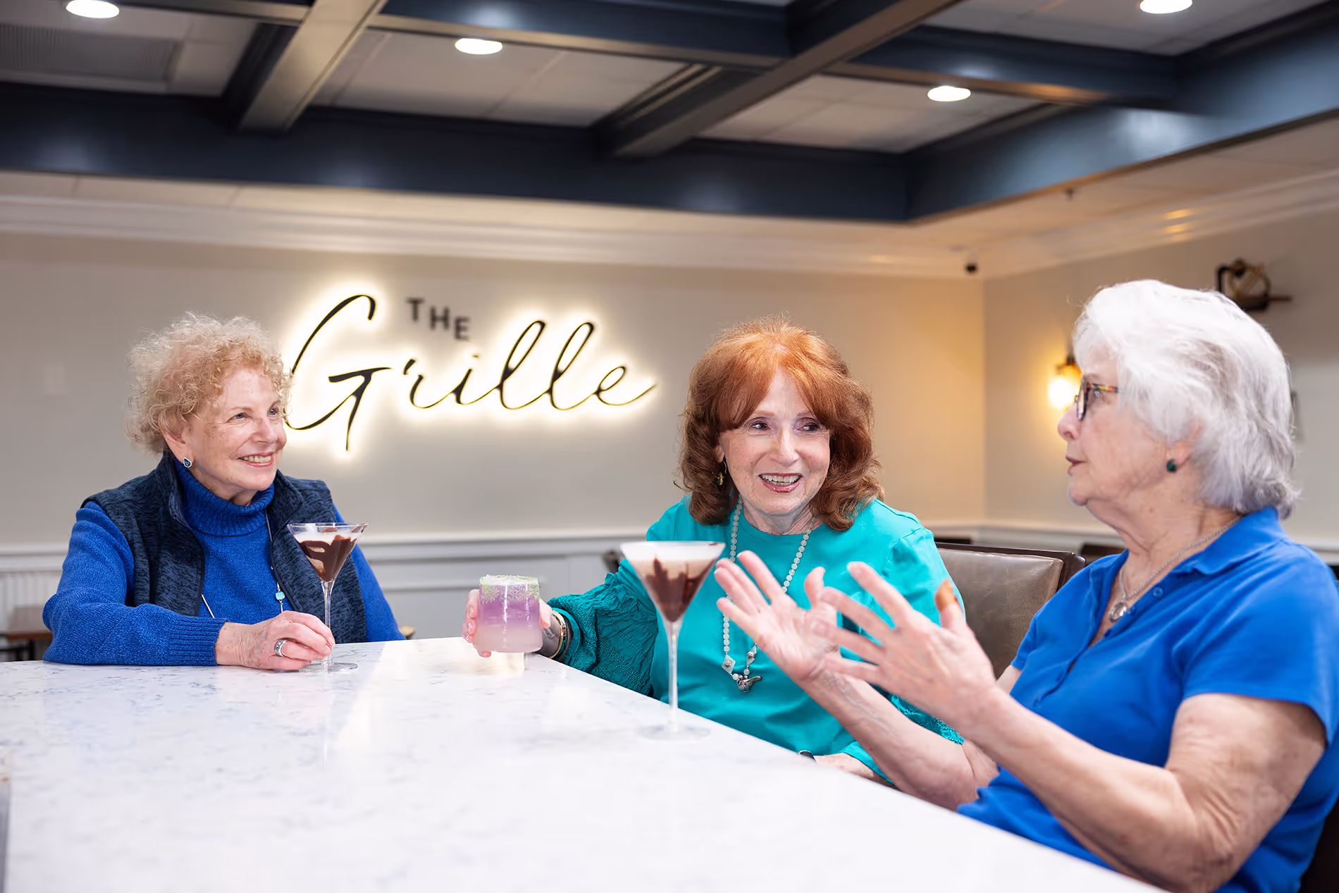 Senior ladies sitting around the bar at the Grille, enjoying drinks, conversation, and a fun, relaxed atmosphere.
