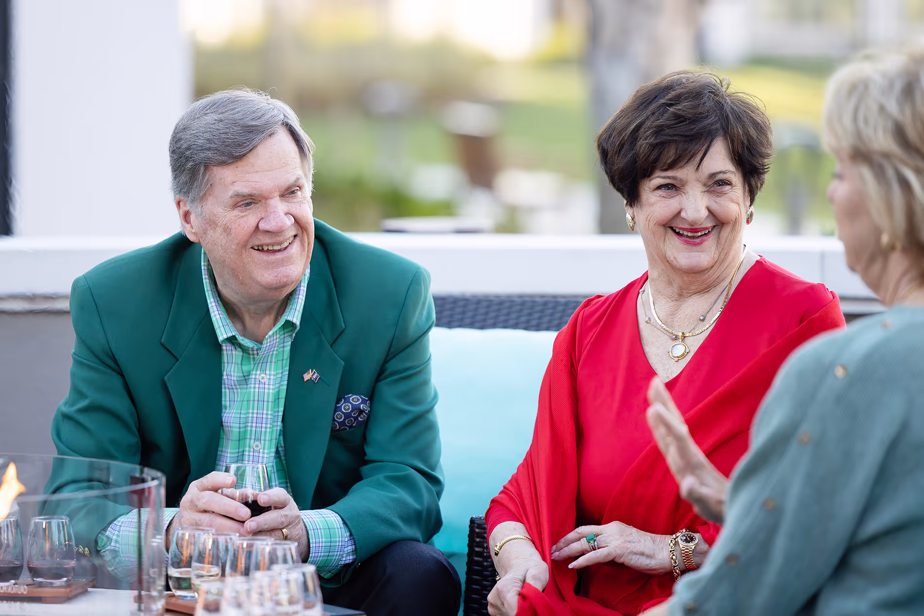 Seniors relaxing on the outdoor patio with glasses of wine, enjoying pleasant weather and good conversation in a comfortable setting.