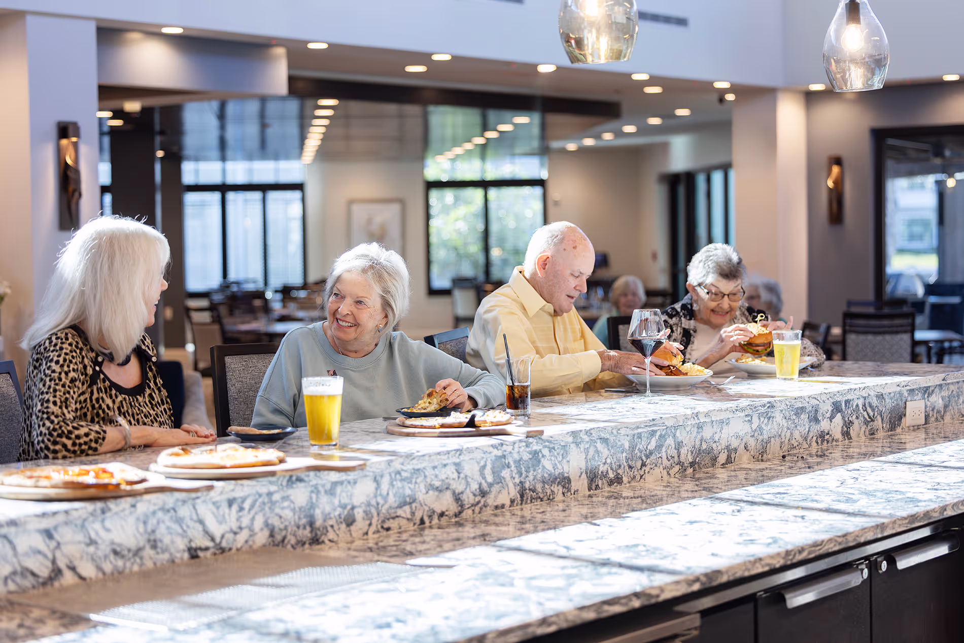 Seniors sitting at a bar enjoying freshly made pizza, showcasing one of the many casual dining options available on campus.