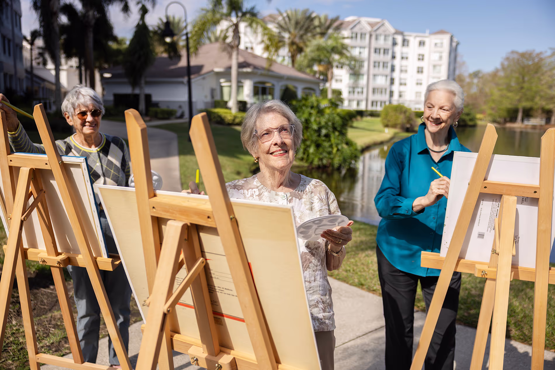 Older women painting outdoors on easels, surrounded by greenery and fresh air, enjoying a relaxing and artistic afternoon.