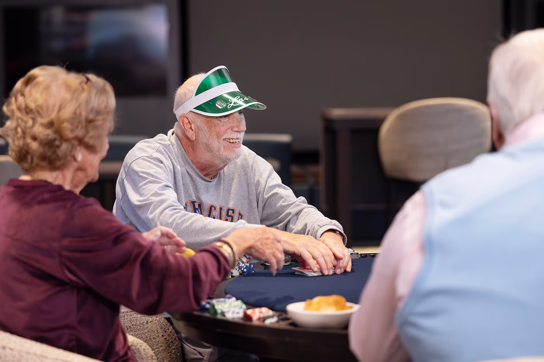 Group of older adults playing poker around a table, laughing and enjoying a lively game together.