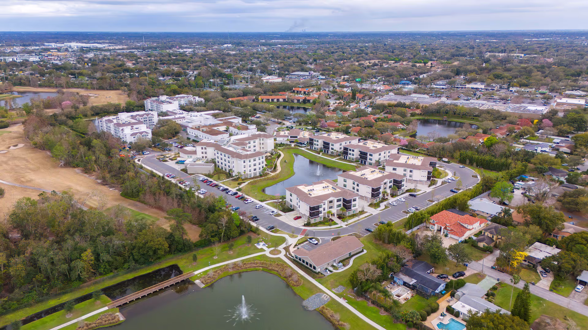 Aerial view of a retirement community campus, showing the layout of buildings, green spaces, and walking paths in a peaceful environment.