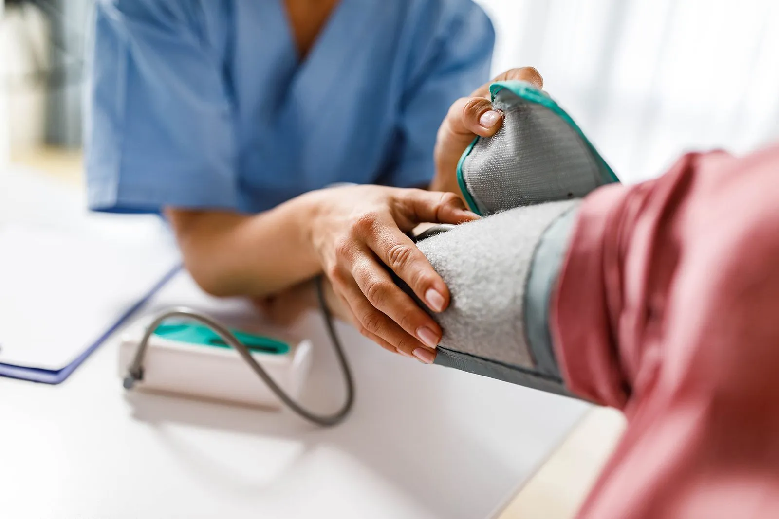 Nurse gently placing a blood pressure cuff on a patient's arm during a routine checkup.