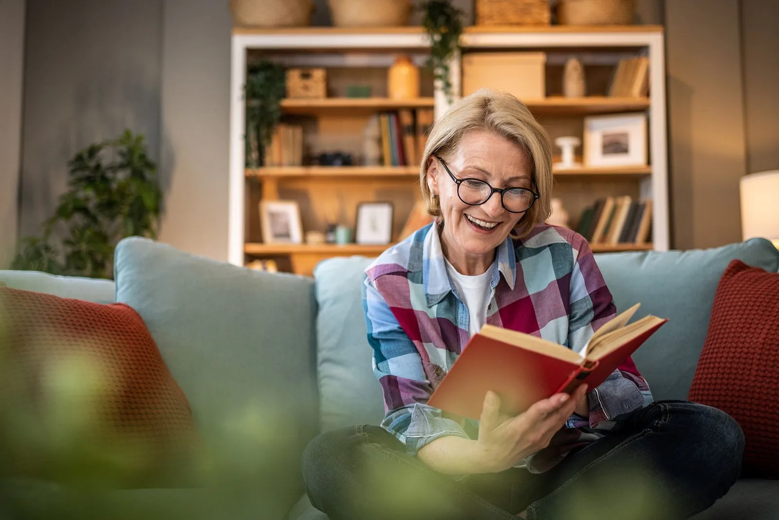 Woman reading a book while surrounded by shelves full of books, fully immersed in her reading.