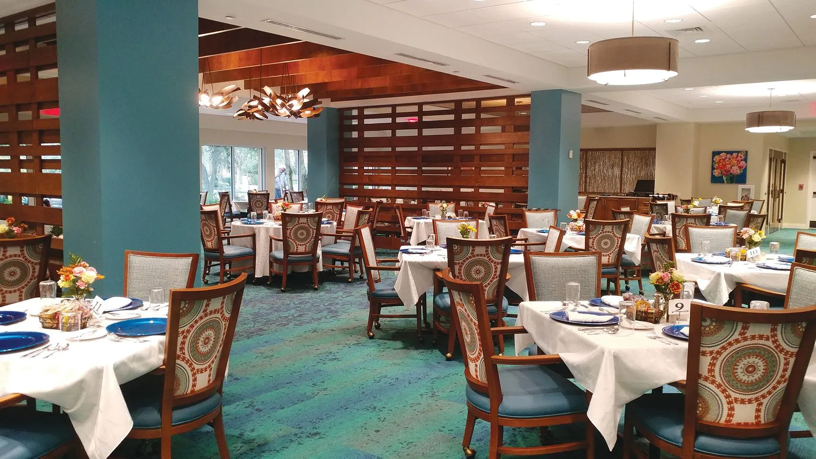 Spacious empty dining room with neatly arranged tables and chairs, natural light streaming through large windows.