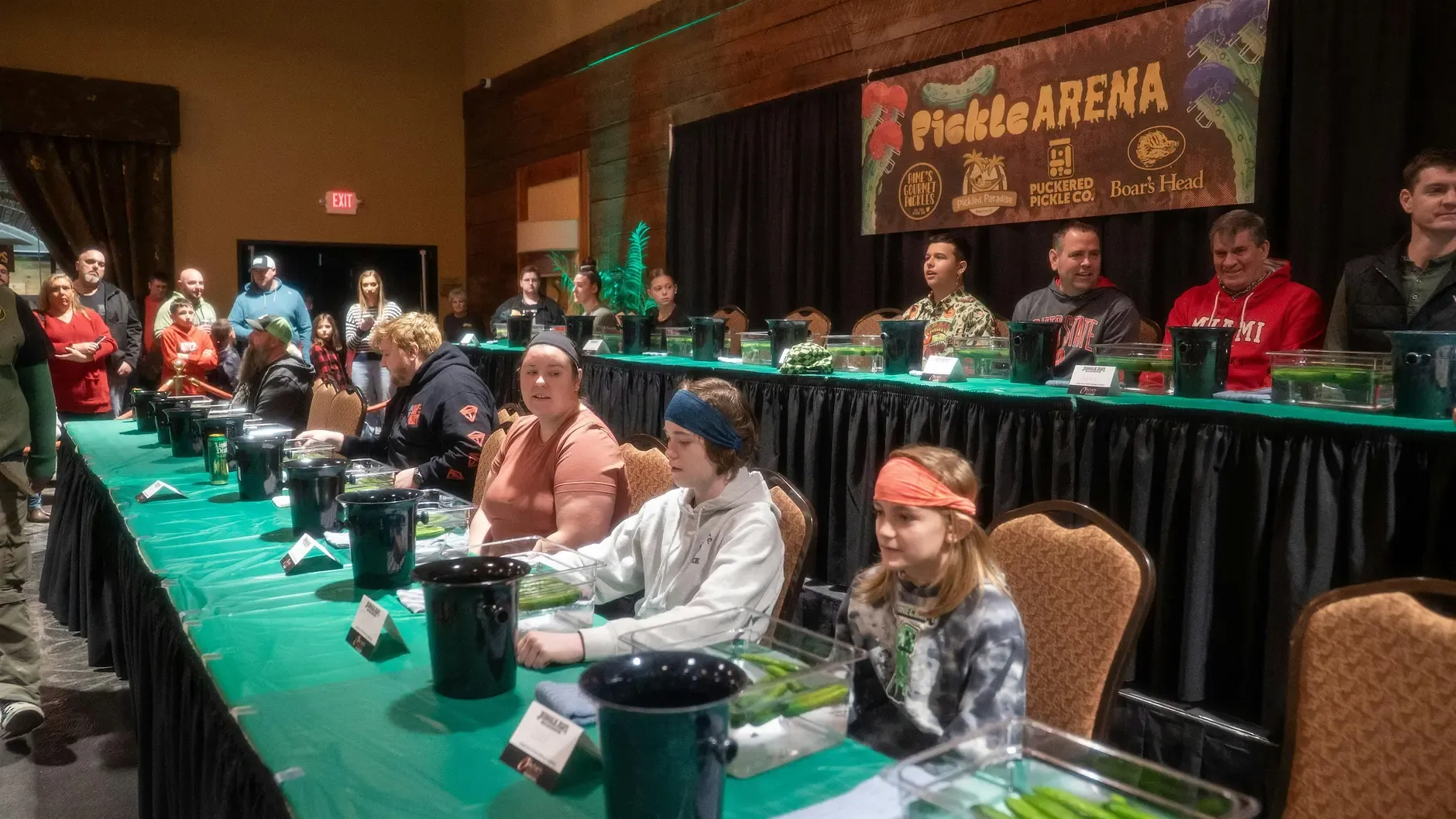Pickle Wars contestants seated at a long competition table