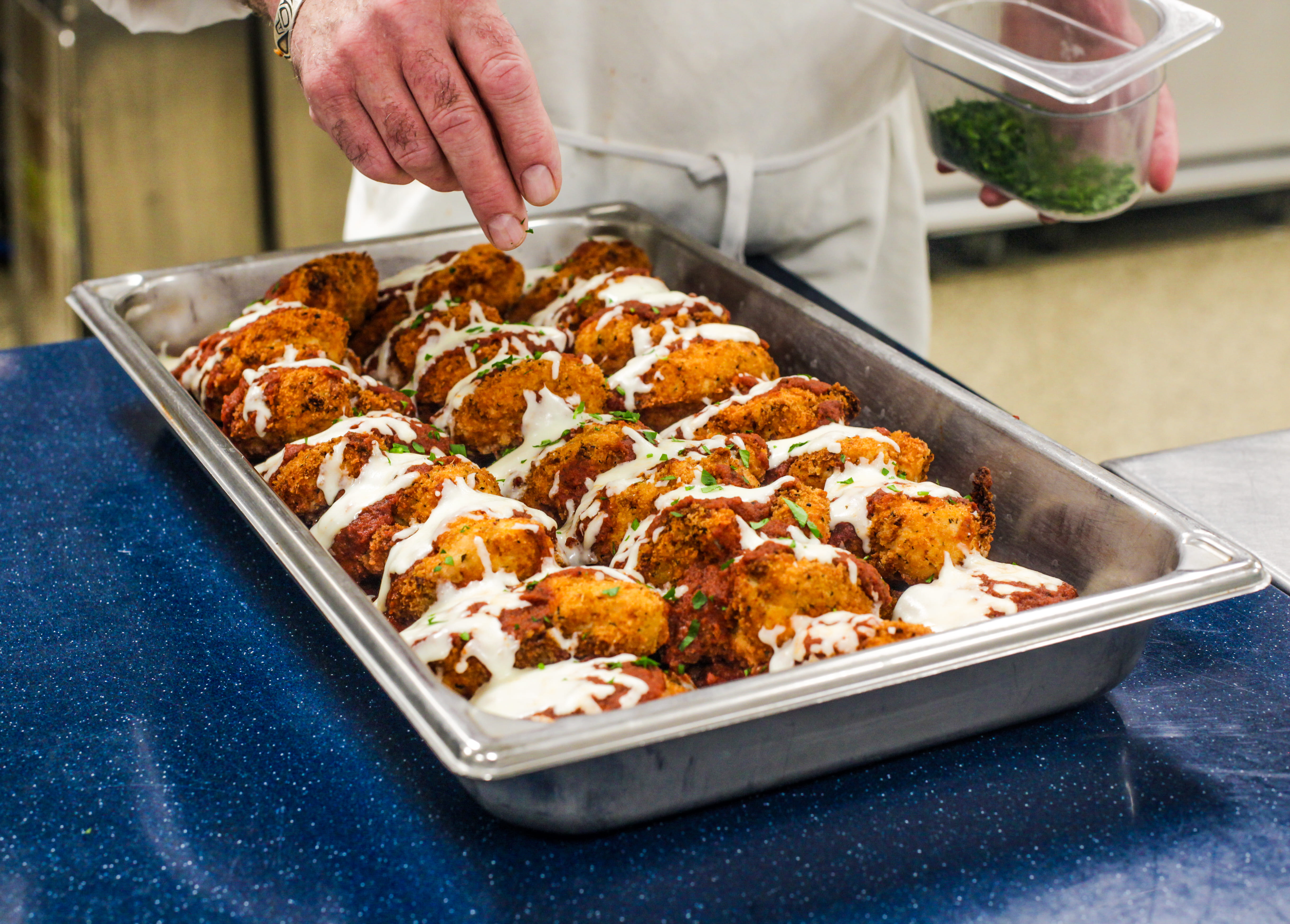 Chef garnishing a tray of catered entrees