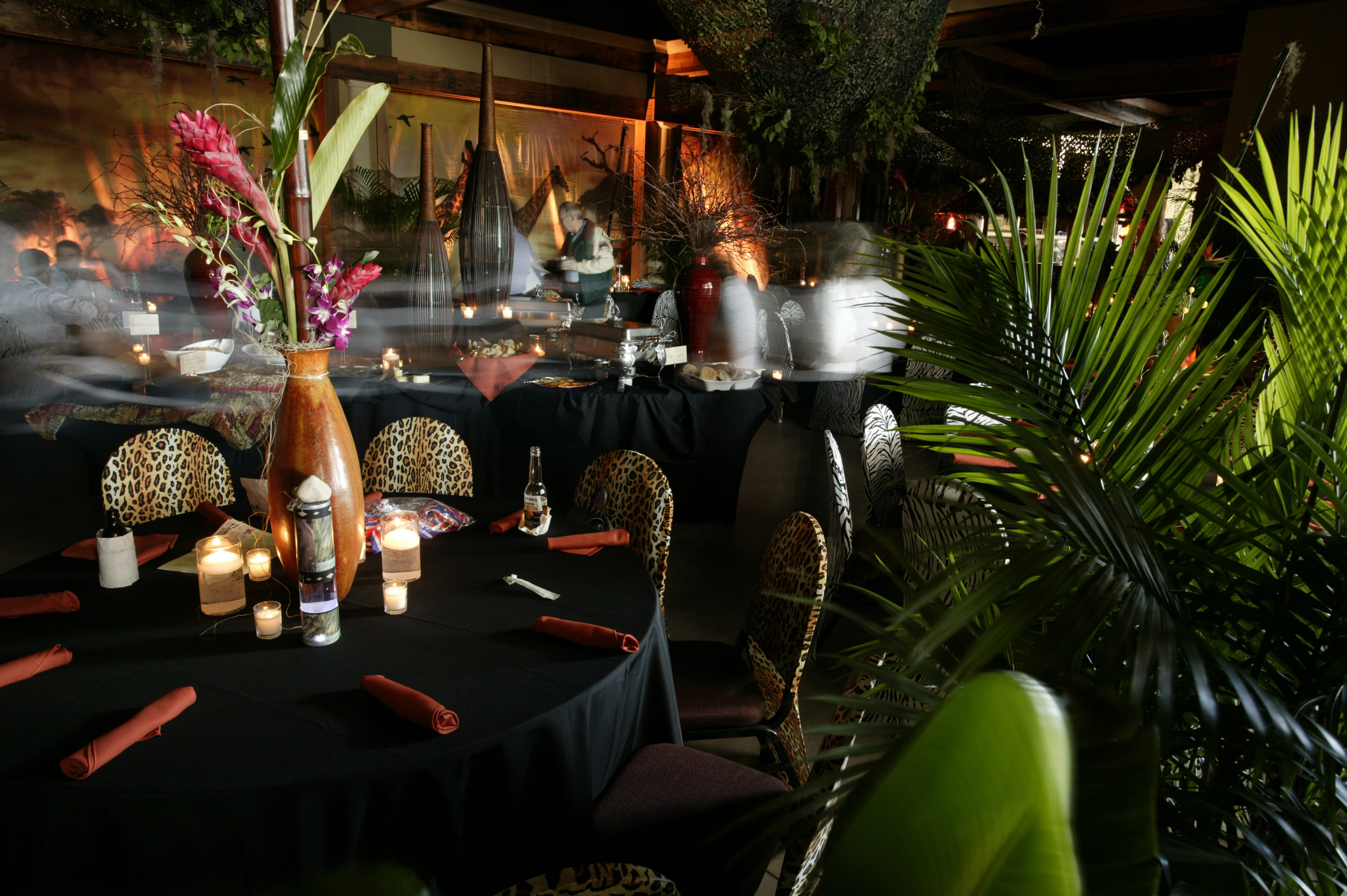 Tropical event dining area with decorated tables and palm plants