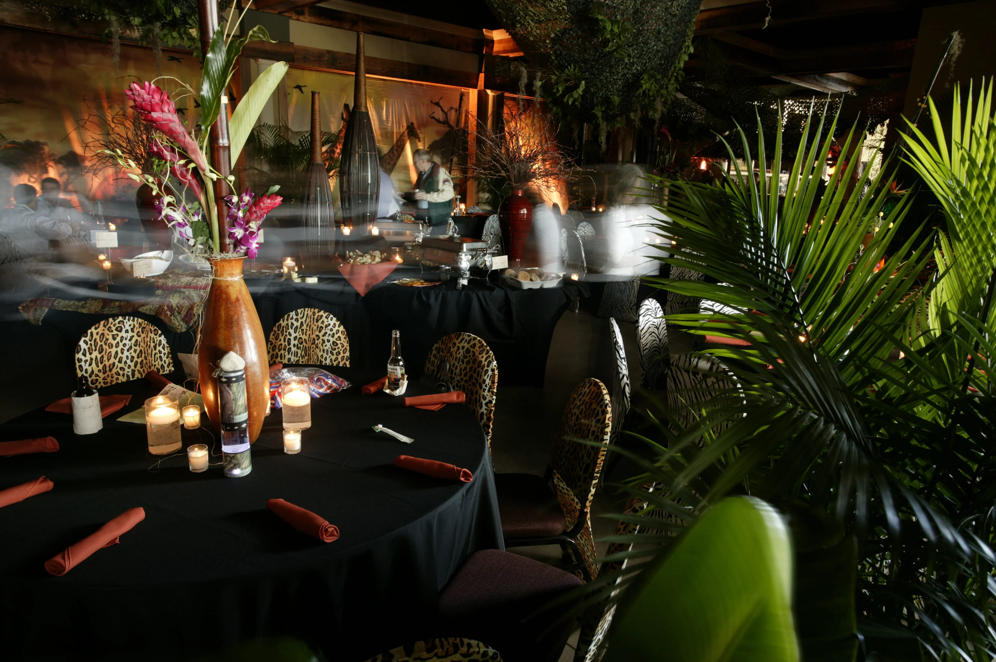 Tropical event dining area with decorated tables and palm plants