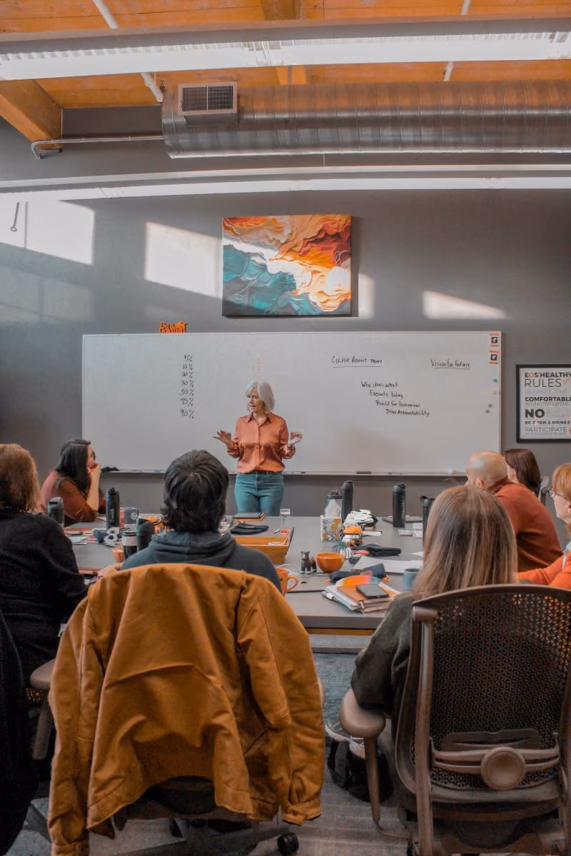 Kirsten leading the Beacon & Blade team around a conference table.