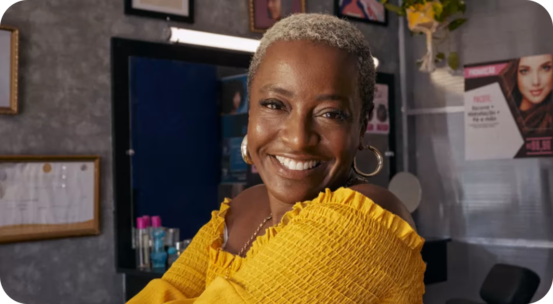 Mulher sorridente com cabelo curto e blusa amarela no salão de beleza.