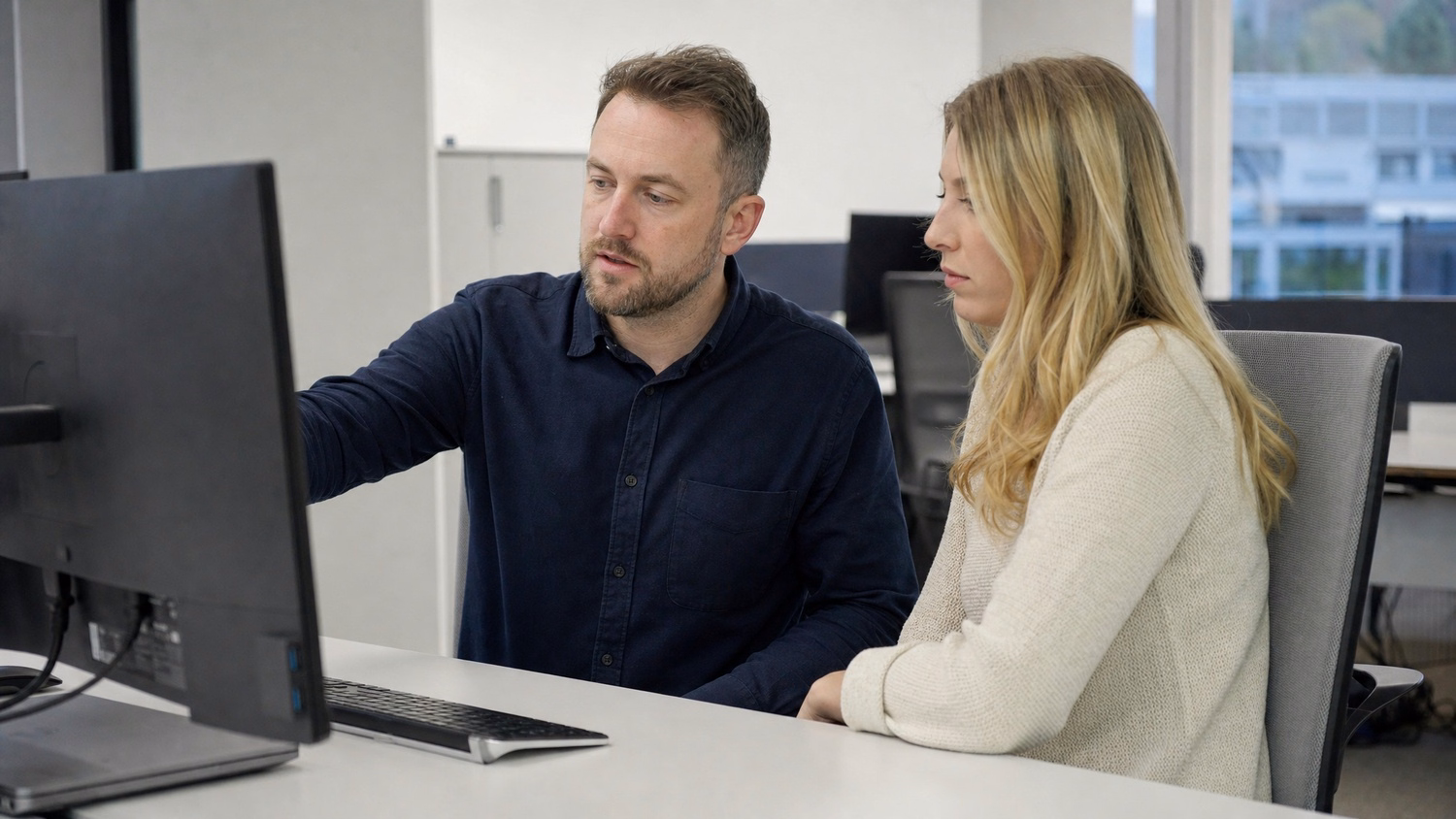SIDE-BY-SIDE PAIR An IT professional two people seated side by side reviewin