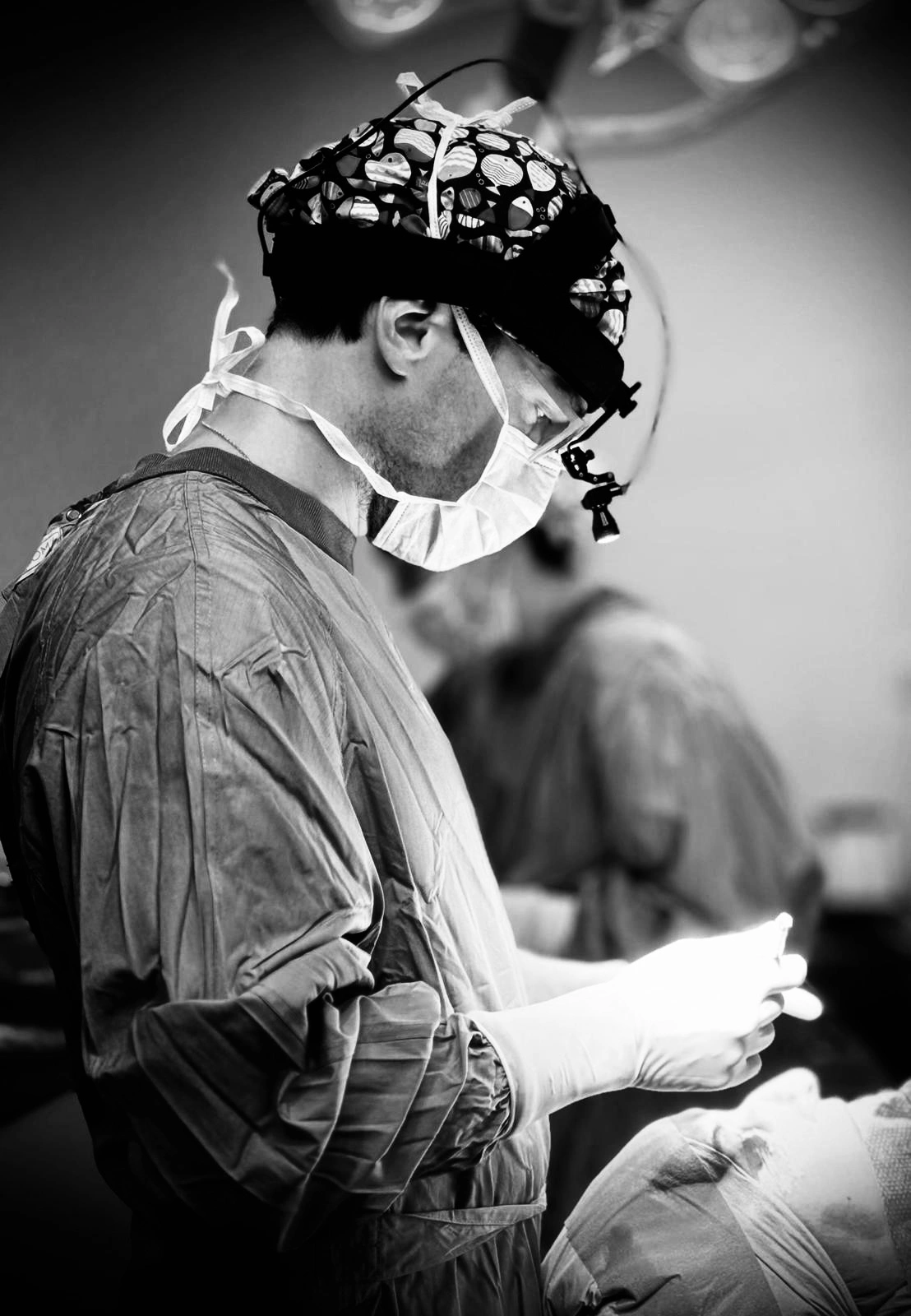 Dr. Ramón Tarragona de ARQÉA Clinic con mascarilla y gorro colorido realizando una operación en un paciente en quirófano