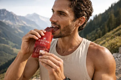 Athletic man eating an Andina Sol energy block in the mountains