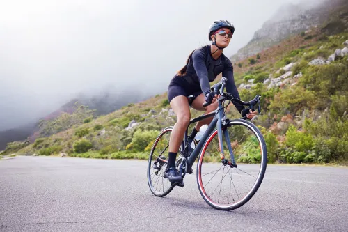 Cyclist riding a road bike on a misty mountain road