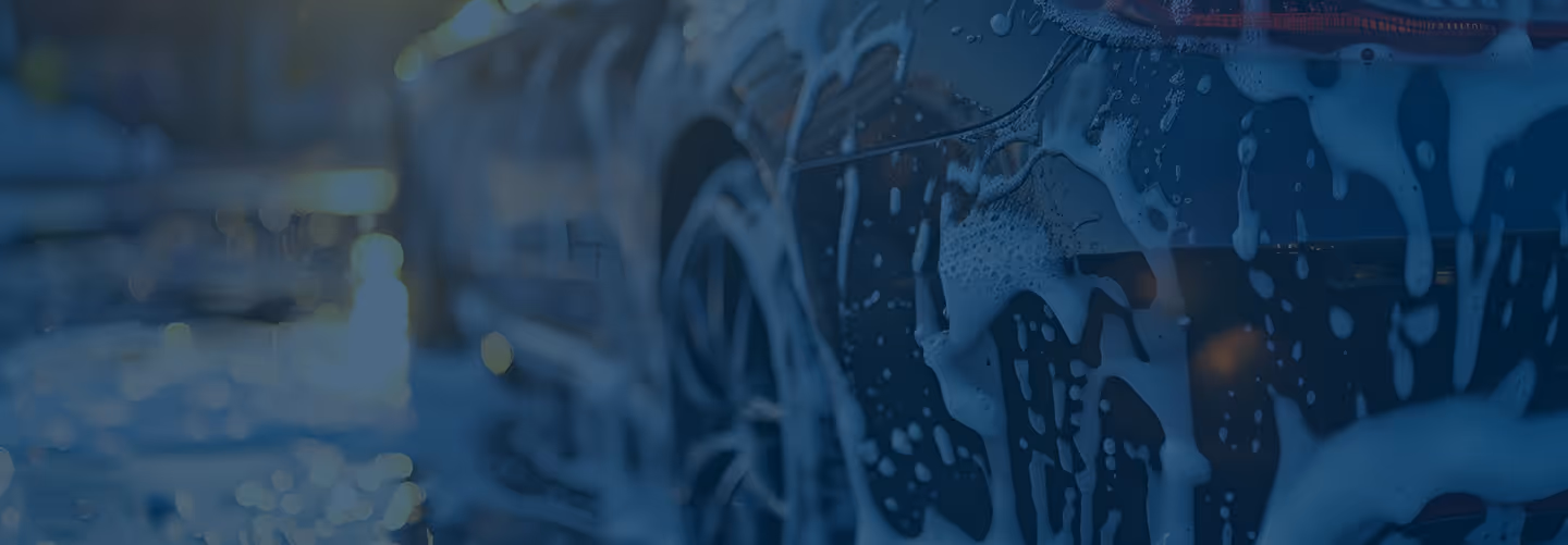 Close-up of a car covered in soap suds during a wash.