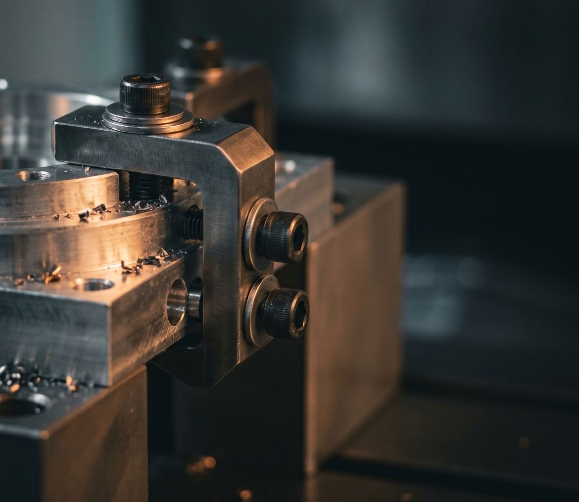 Close-up of a precision metal clamp holding a machined part with metal shavings around it.