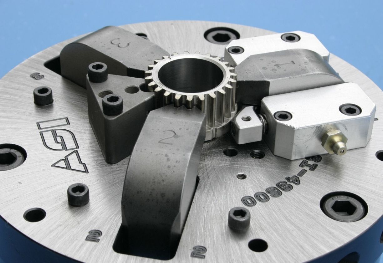 Close-up of metal mechanical component with numbered clamps and a central gear on a brushed metal base.