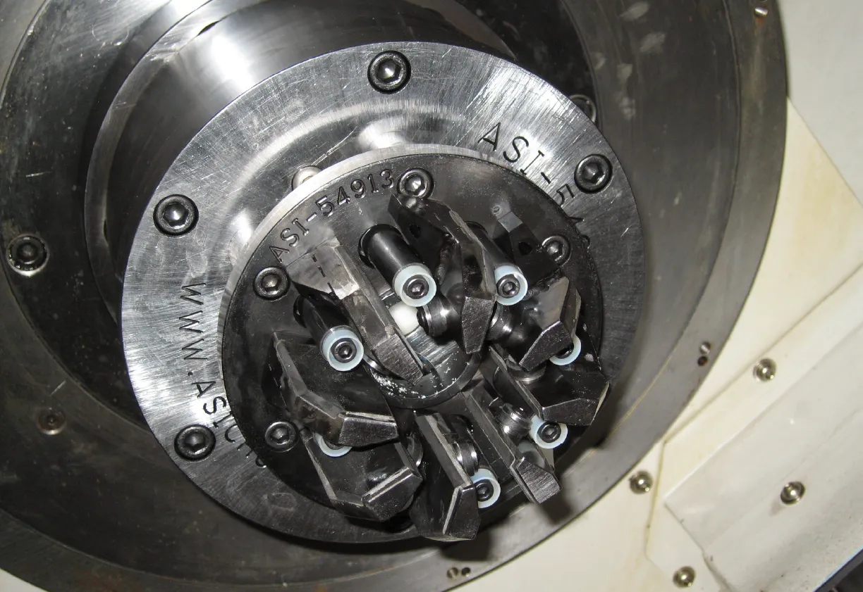 Close-up of a mechanical specialty chucking workholding setup with multiple jaws and screws on a metal circular base.