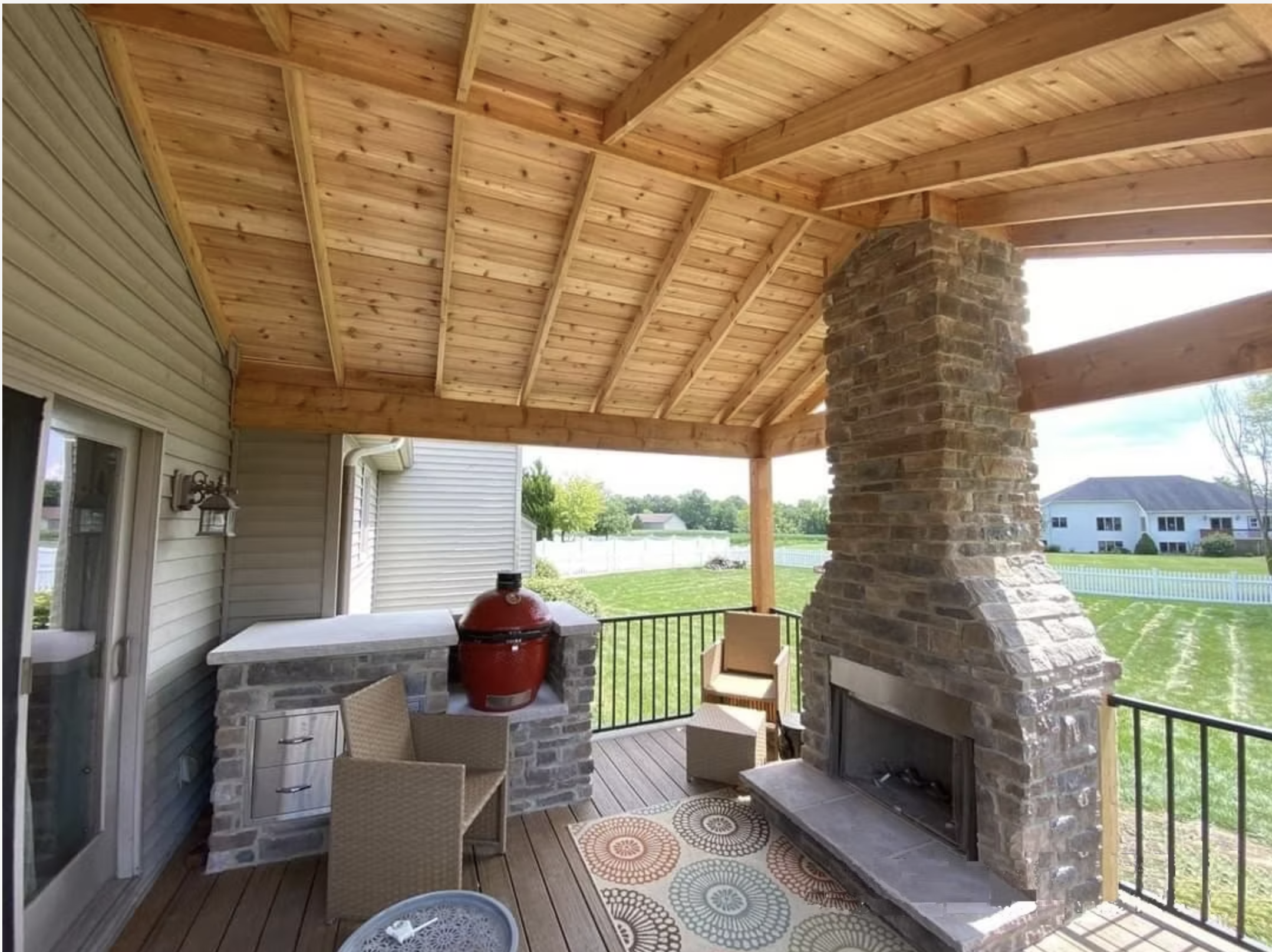 Covered outdoor porch with stone fireplace by Knot Just Decks Fort Wayne