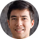Young man with short dark hair smiling against a neutral background.