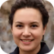 Smiling woman with short curly hair and dark jacket in an outdoor setting.