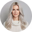 Portrait of a woman with long blonde hair wearing a white sweater against a neutral background.