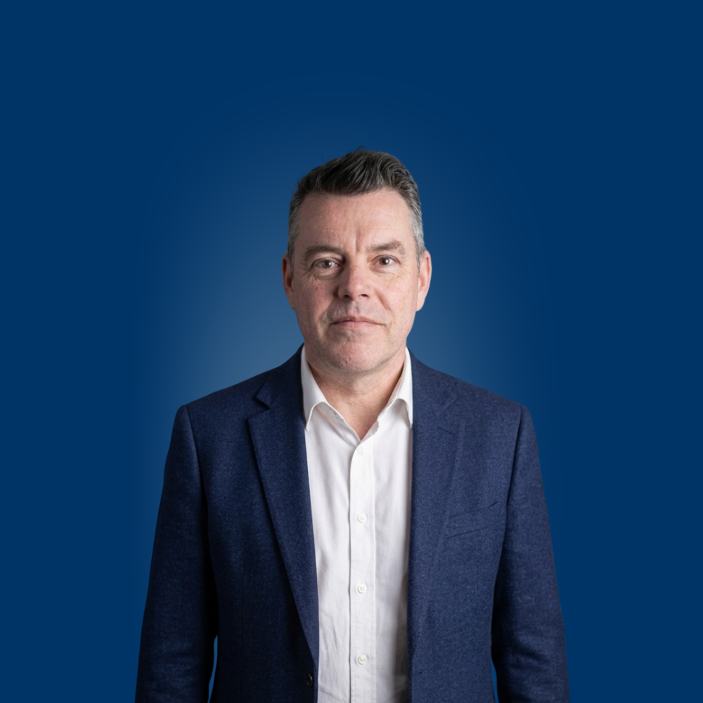 Portrait of a young woman with long blonde hair and glasses wearing a light blue shirt.