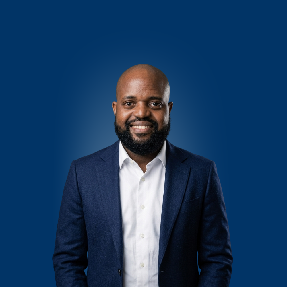 Portrait of a young woman with long blonde hair and glasses wearing a light blue shirt.