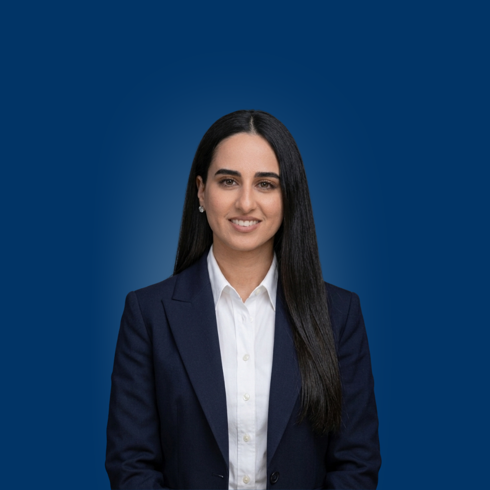 Portrait of a young woman with long blonde hair and glasses wearing a light blue shirt.
