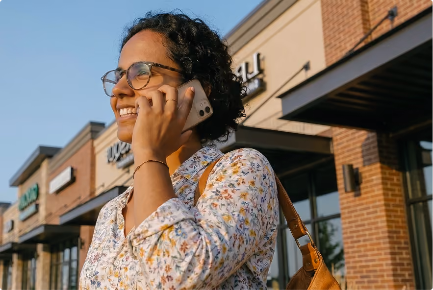 Woman talking on a smartphone outside a shopping center.