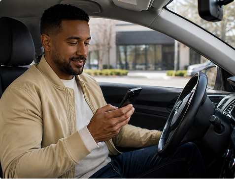 Driver using a smartphone to communicate with an insurance provider while seated in a vehicle.