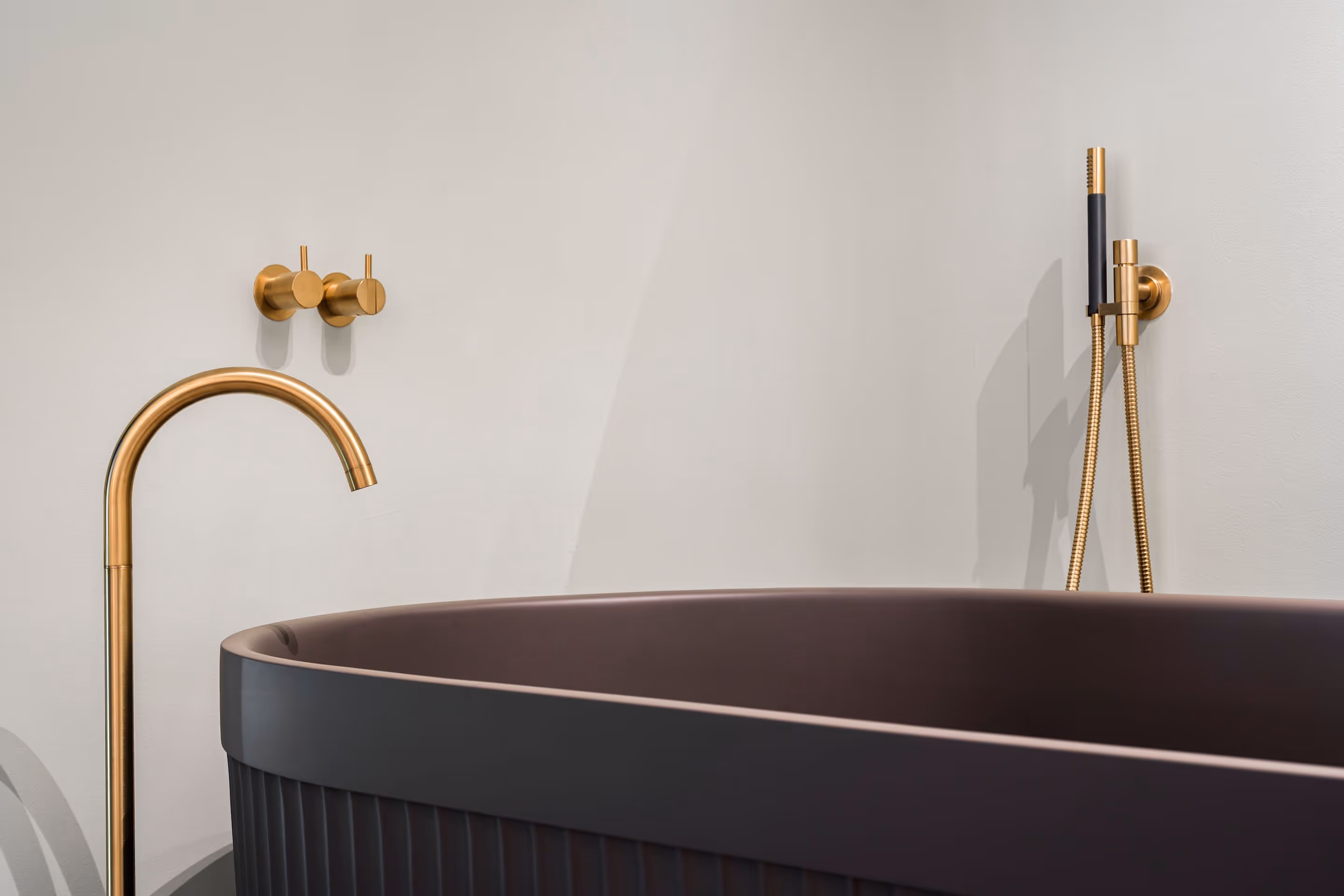 Japandi badkamer met donkergrijs geribbeld bad en gouden badkraan