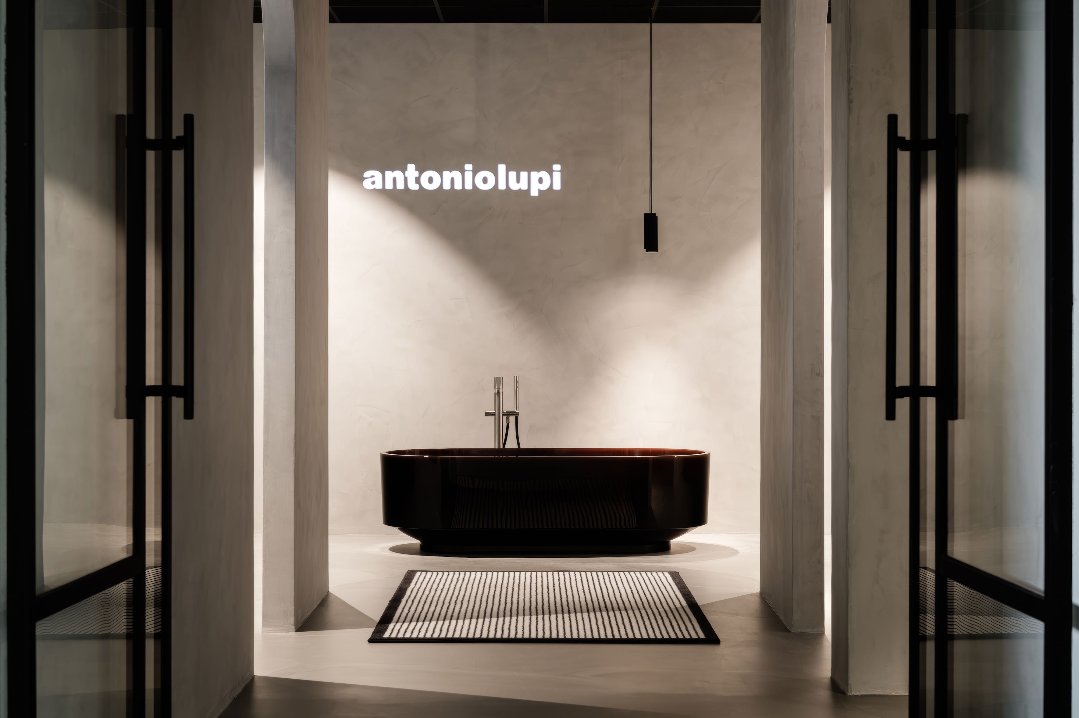Antonio Lupi showroom met een donker rond vrijstaand bad en het merklogo aan de wand