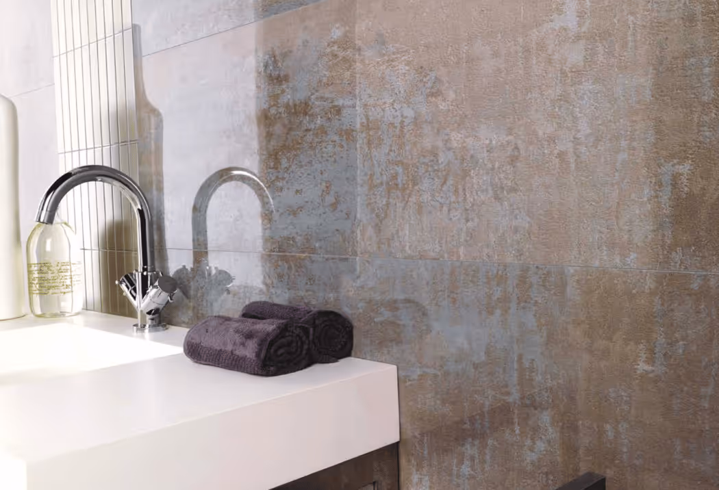 Porcelanosa witte structuurtegel met bronskleurige douchekranen