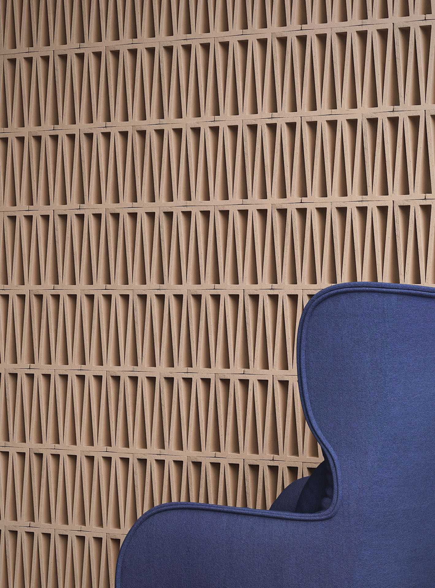 Mutina beige geweven structuurtegel met blauwe fauteuil op voorgrond