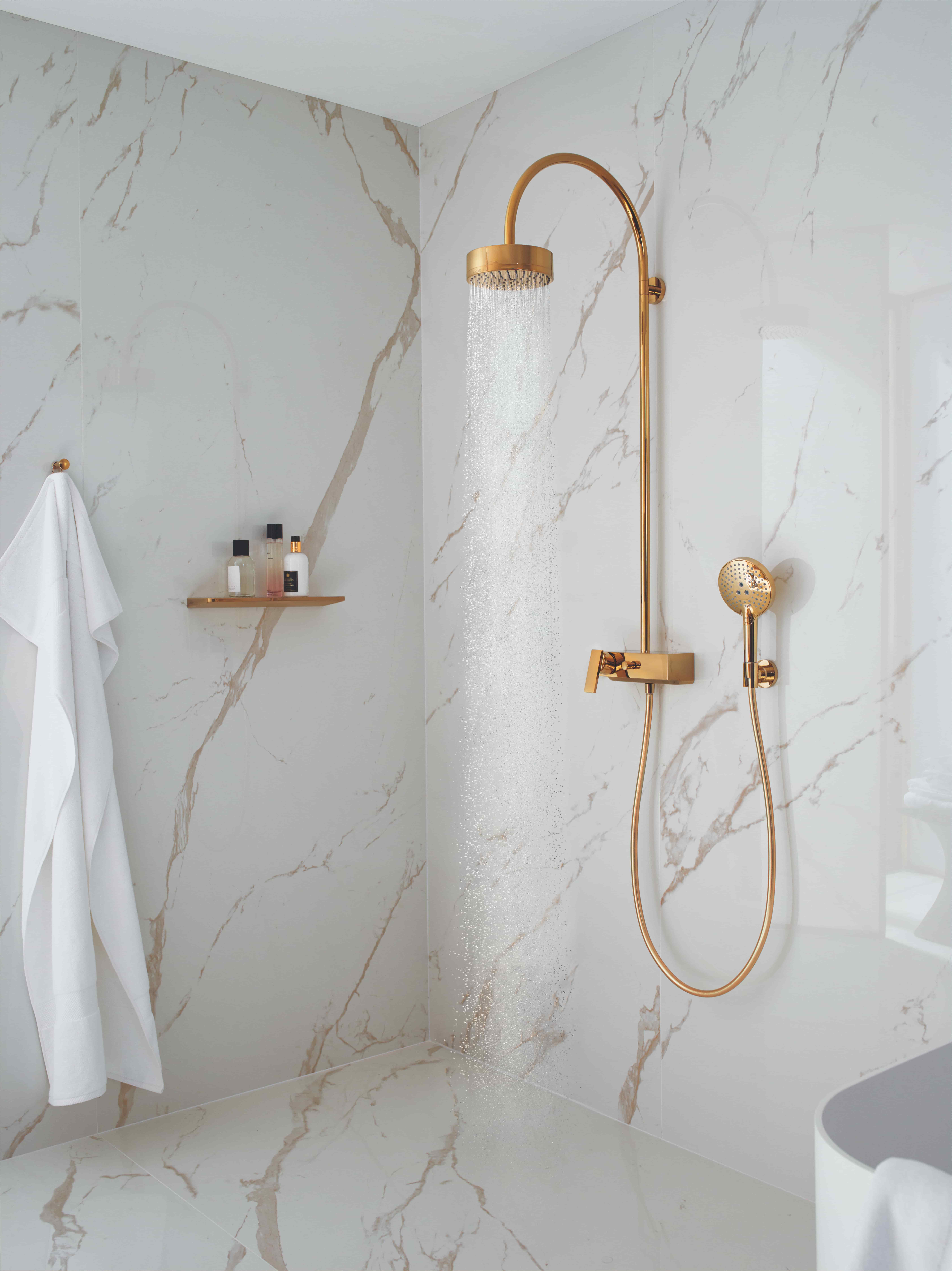 Axor Citterio douchesysteem in goud tegen witte marmeren wand