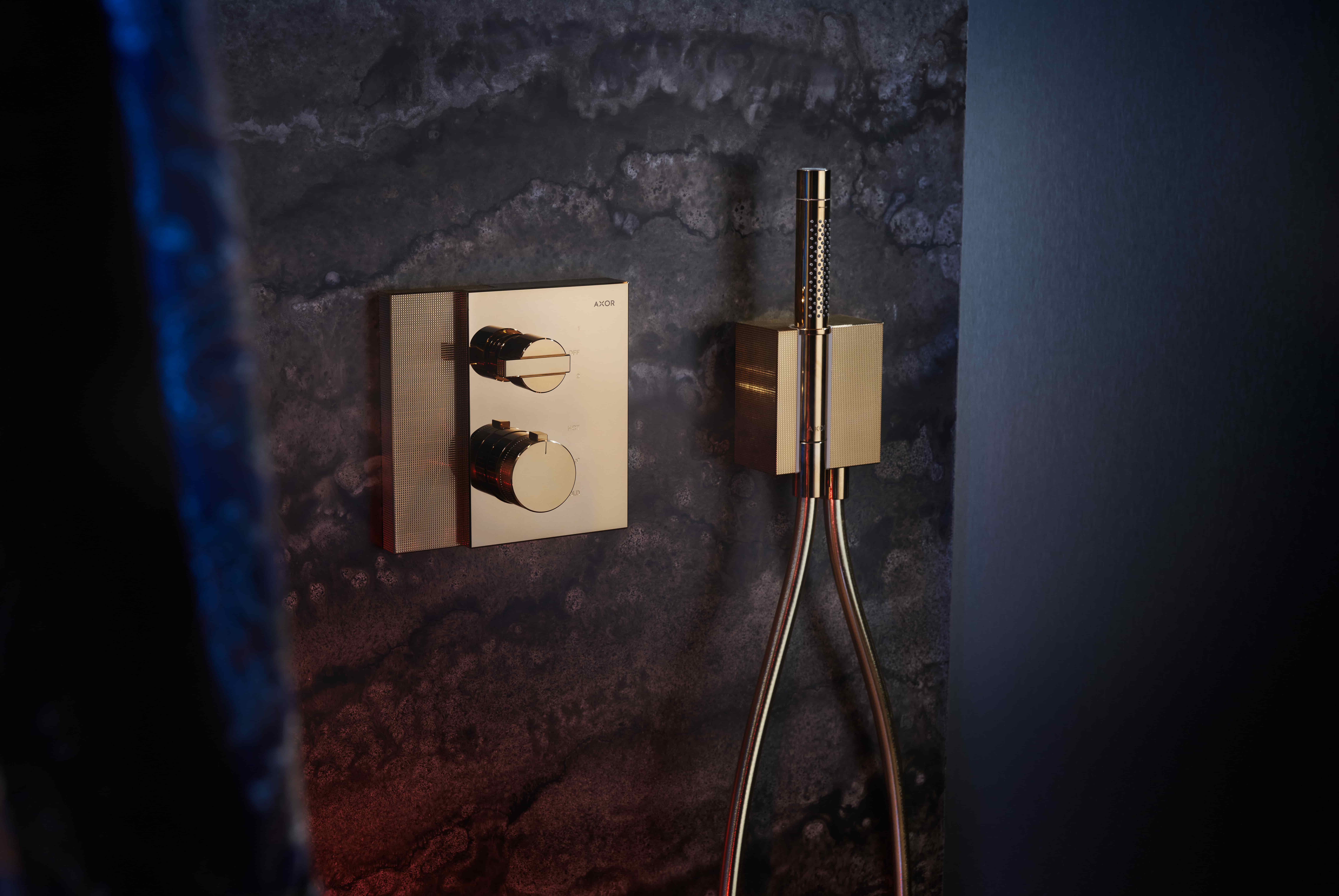 Axor Edge inbouwthermostaat met handdouche in goud tegen donkere natuursteen wand