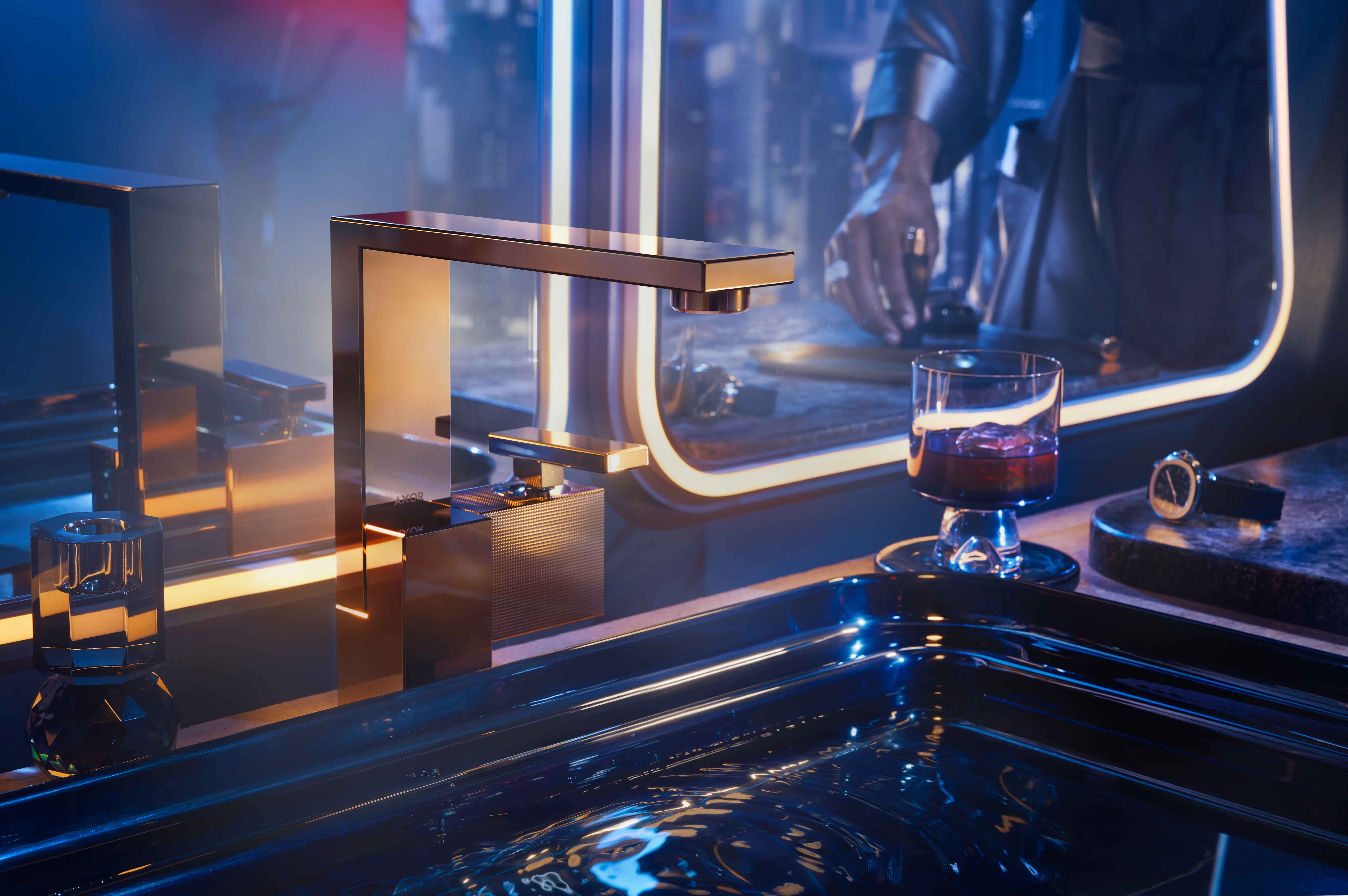 Axor Edge wastafelkraan in goud in sfeervol verlicht interieur met glas drank