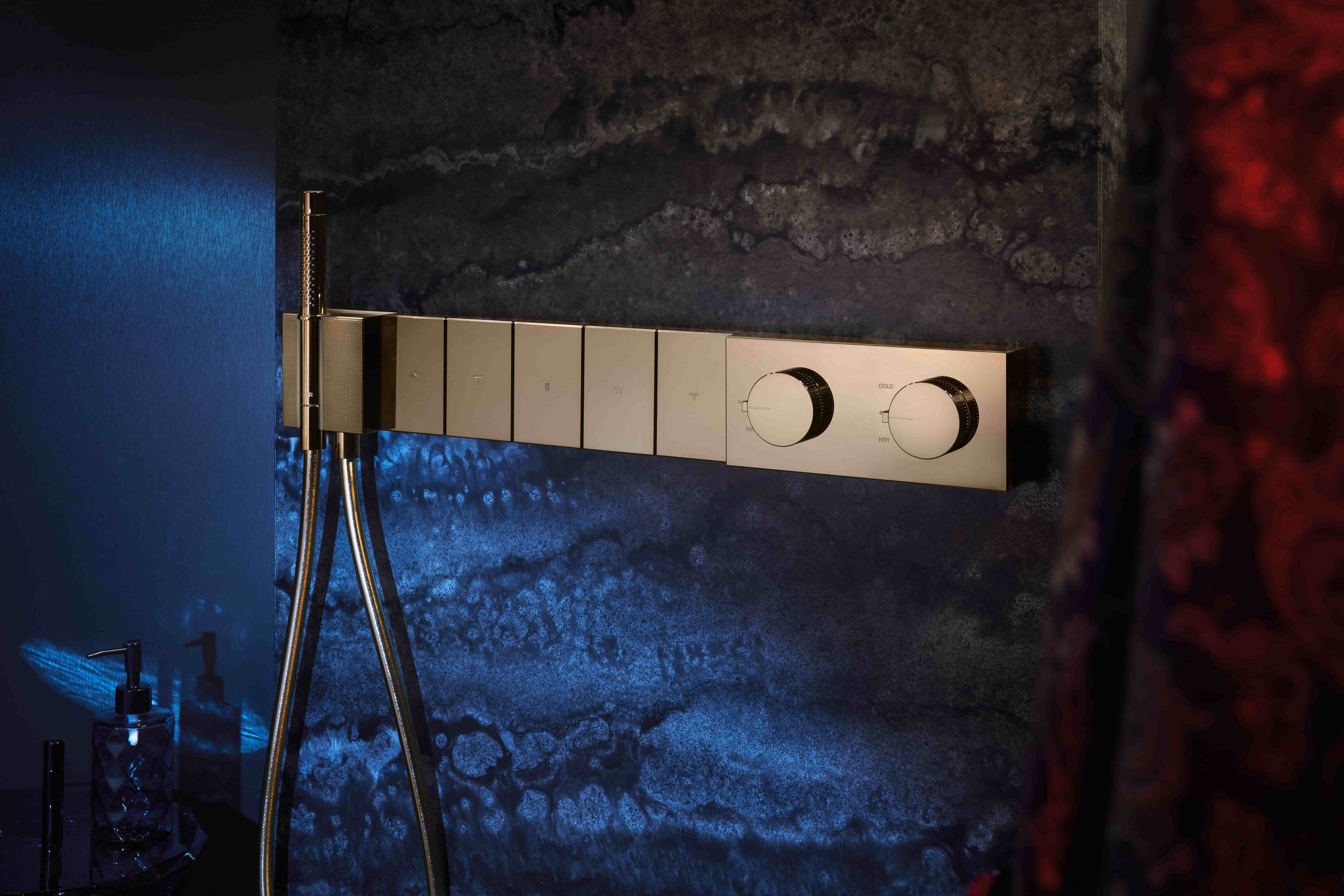 Axor Edge inbouwthermostaat met bedieningsknoppen tegen donkere natuursteen wand