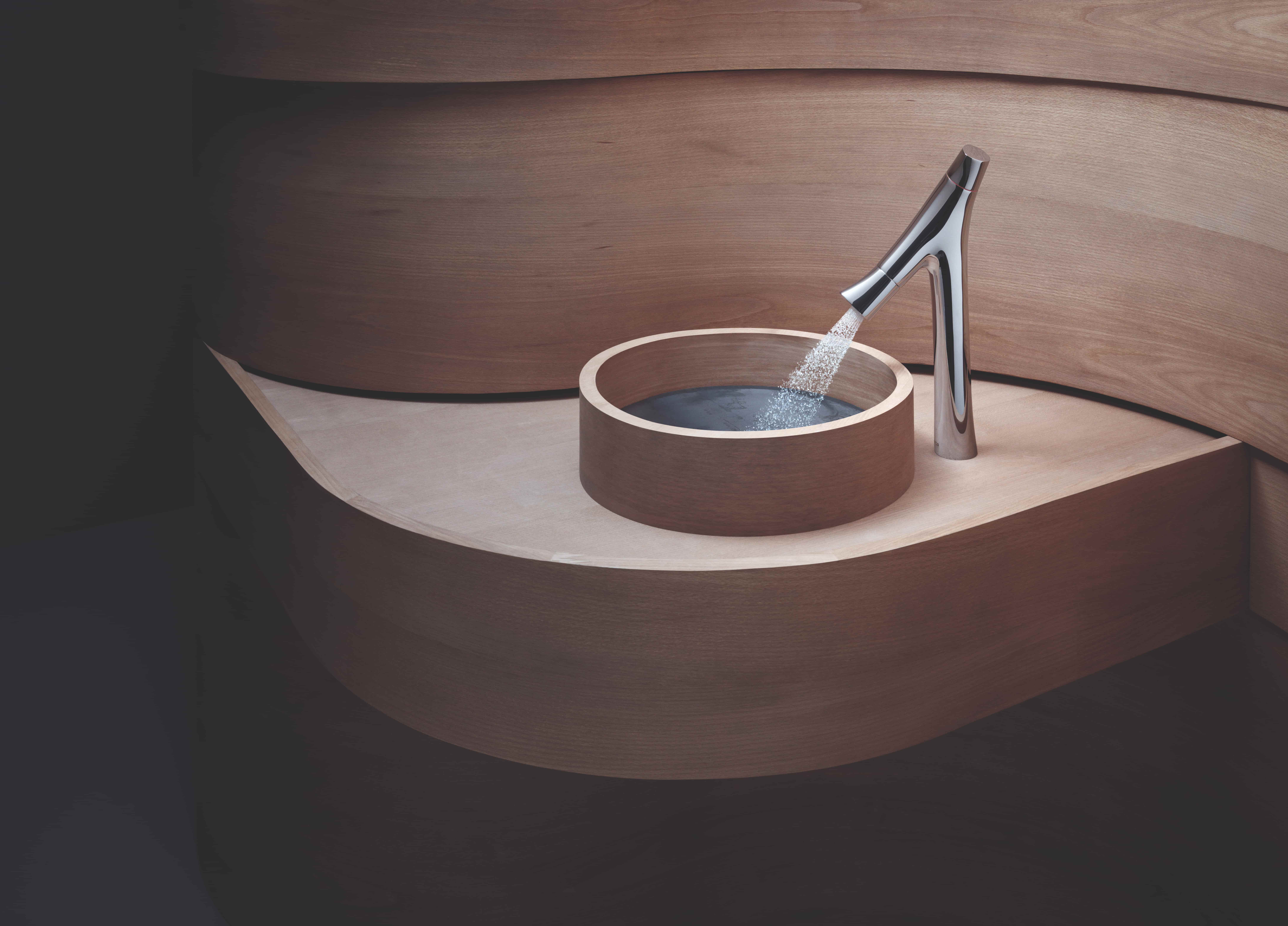 Axor Starck kraan in chroom met hoekig ontwerp boven een ronde houten wasbak