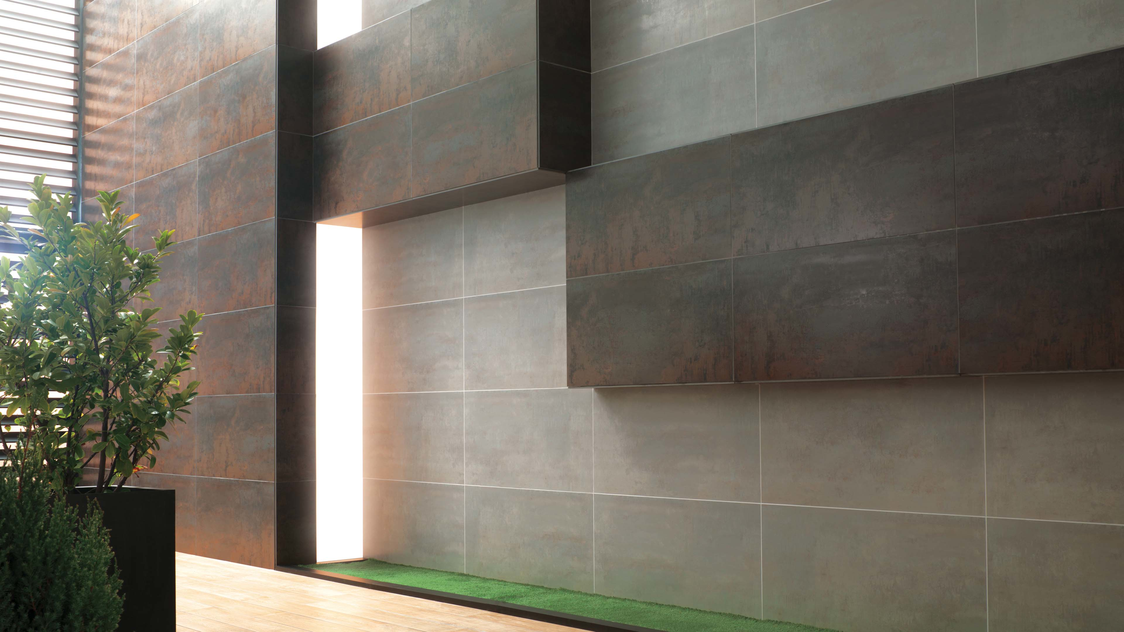 Hal met Porcelanosa Ferroker tegelcombinatie in roest en grijs, met plant