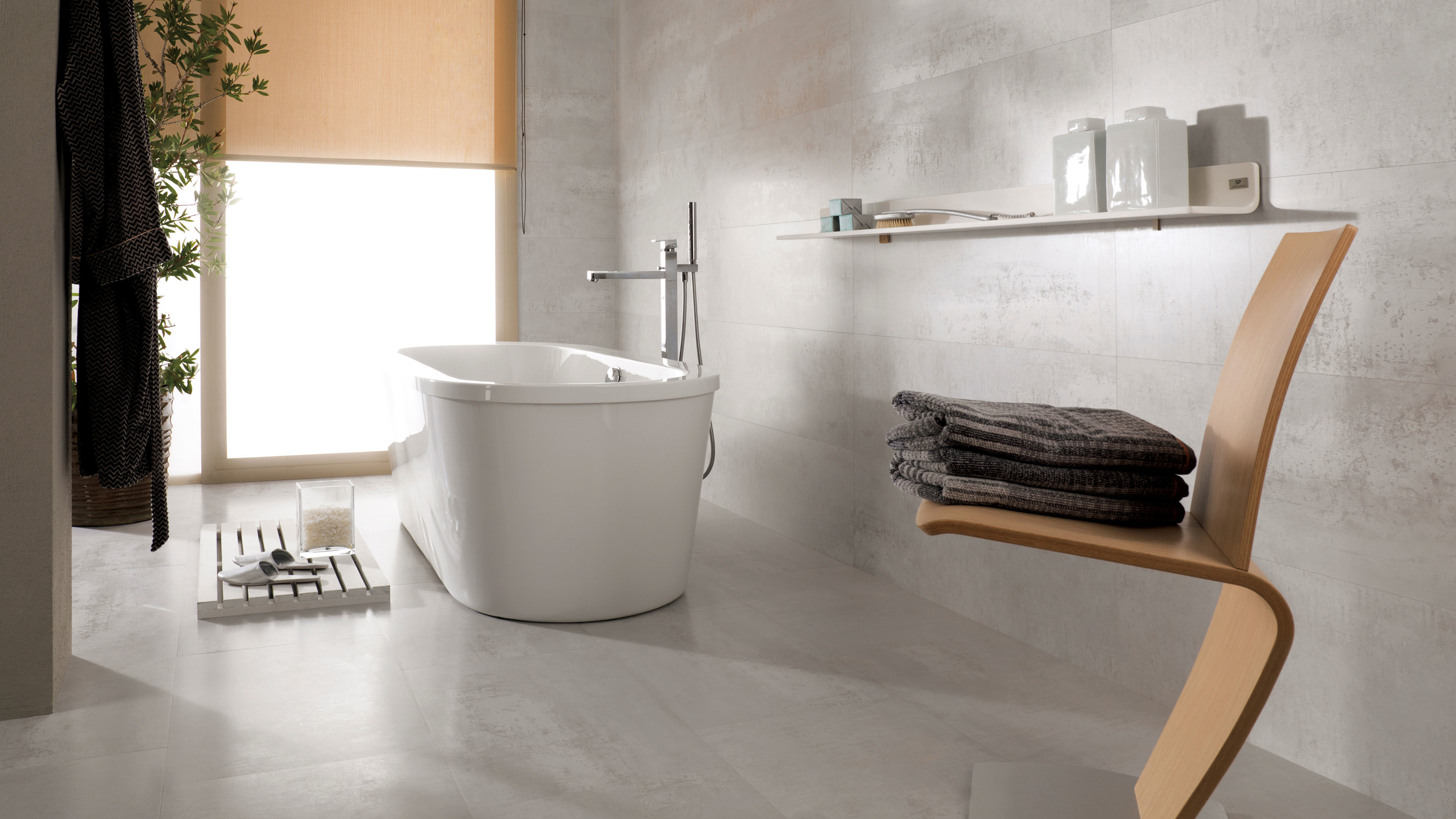 Badkamer met Porcelanosa Ferroker Platino tegel en vrijstaand wit bad