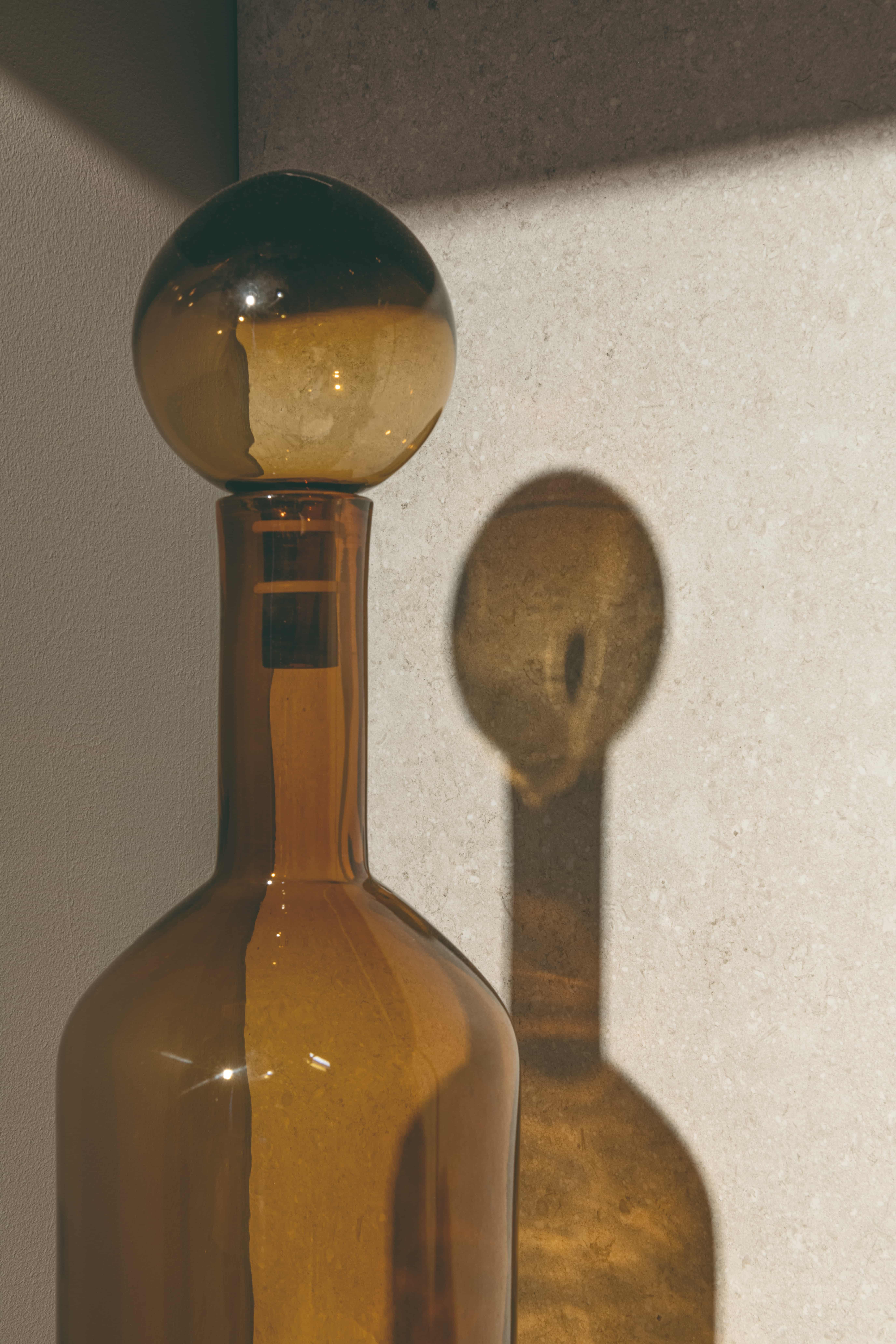 La Faenza GEA S RM tegel als achtergrond bij een amberkleurige glazen fles in zonlicht