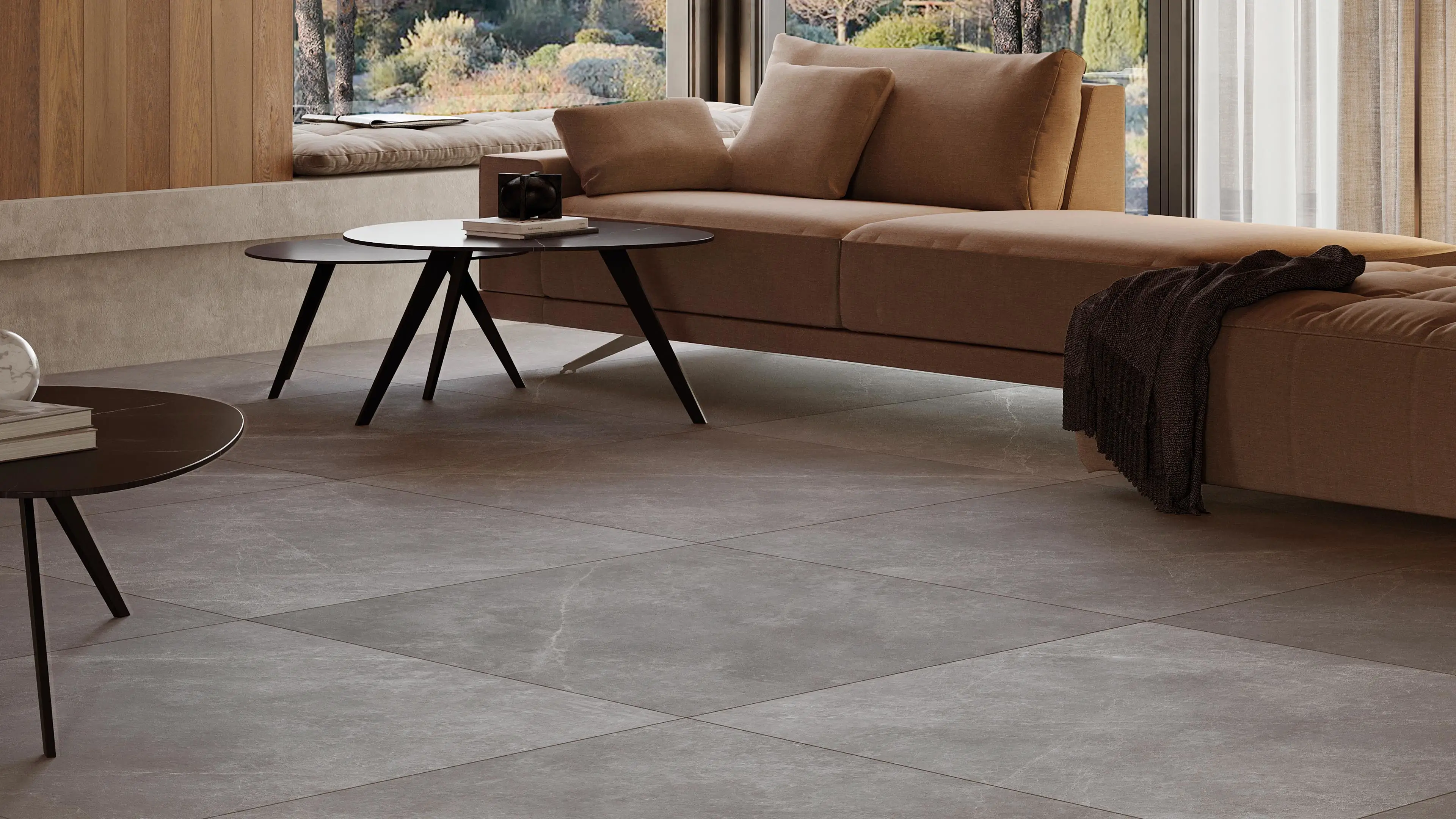 Woonkamer met Porcelanosa Mysic Grey vloertegel, bruine bank en ronde salontafels