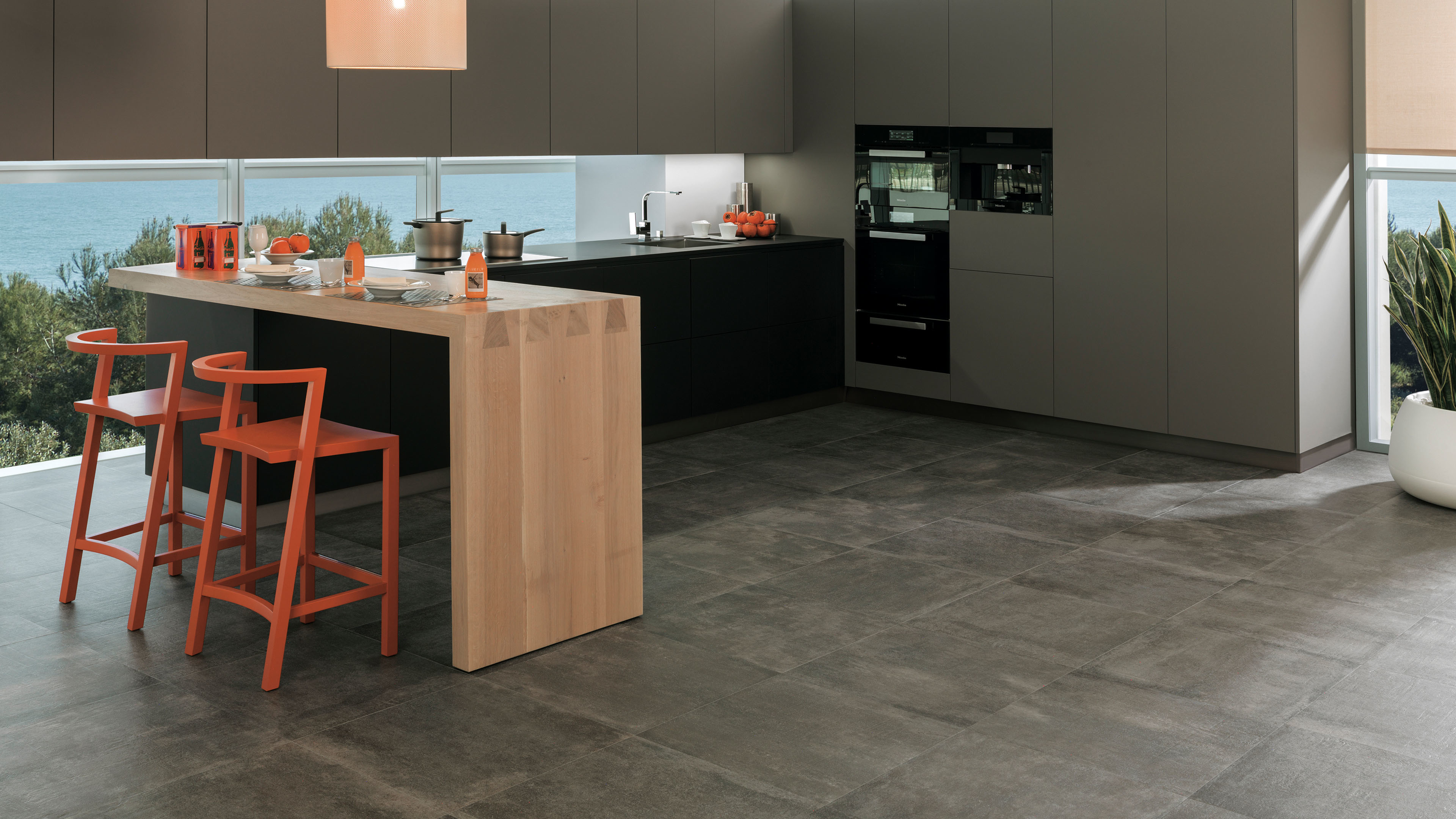 Keuken met Porcelanosa Newport Dark Gray vloertegel, donkere kastenwand en zeezicht