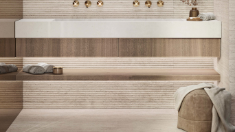 Porcelanosa Taranto Bone tegel rond inbouwbad met houten paneel en gouden kranen