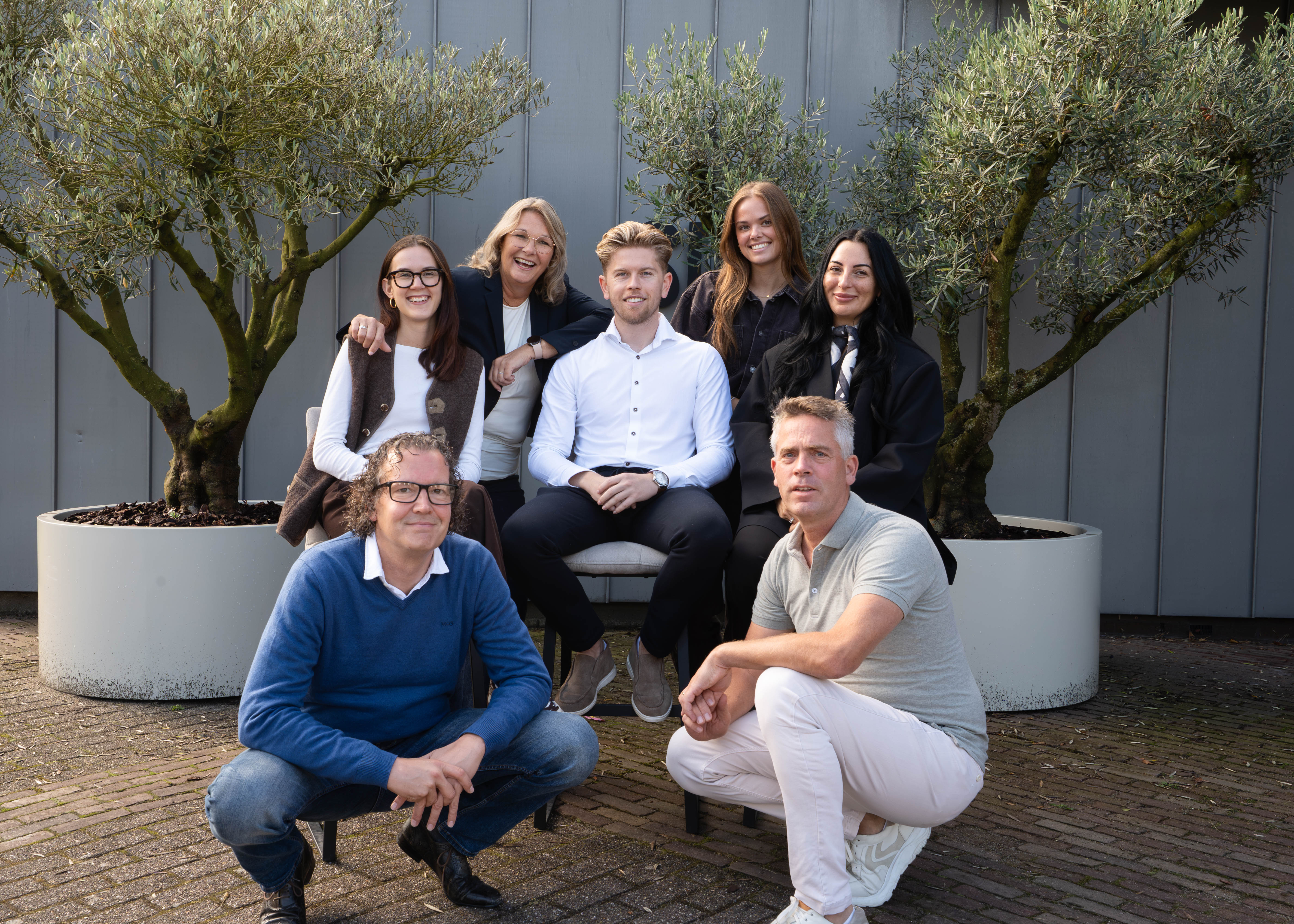 Team van Sanitair Design Center in een groepsfoto buiten tussen olijfbomen